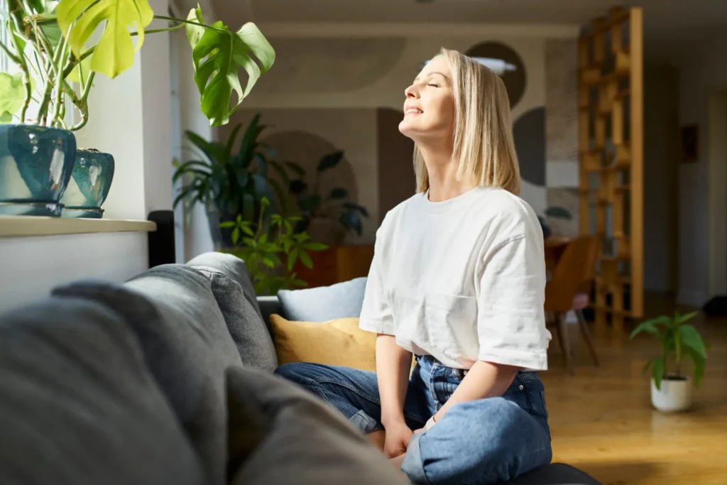 Woman enjoying sunlight on a cozy sofa.