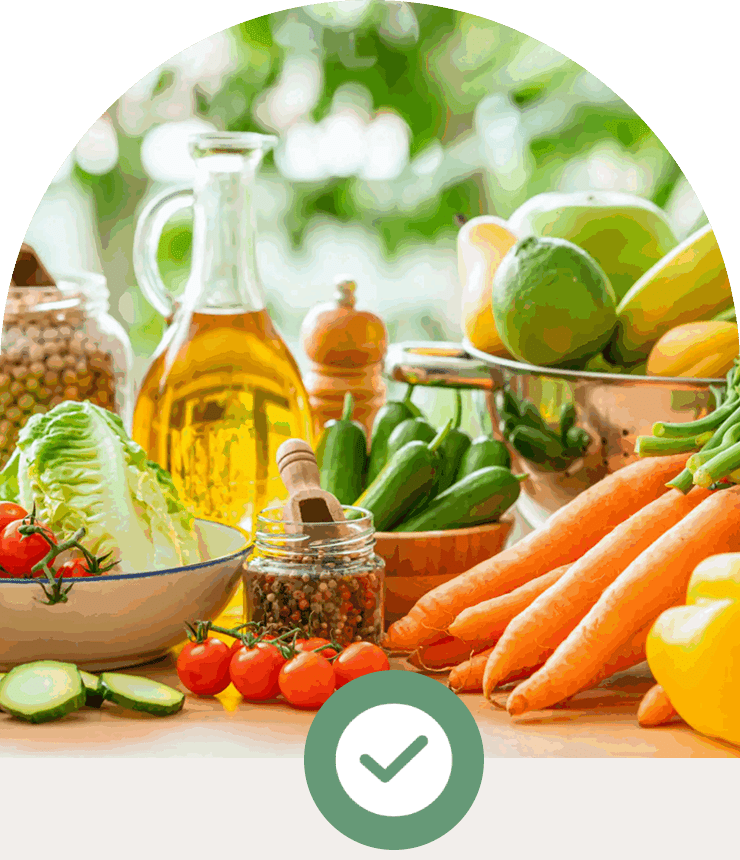 Fresh vegetables and olive oil arranged on a kitchen counter.