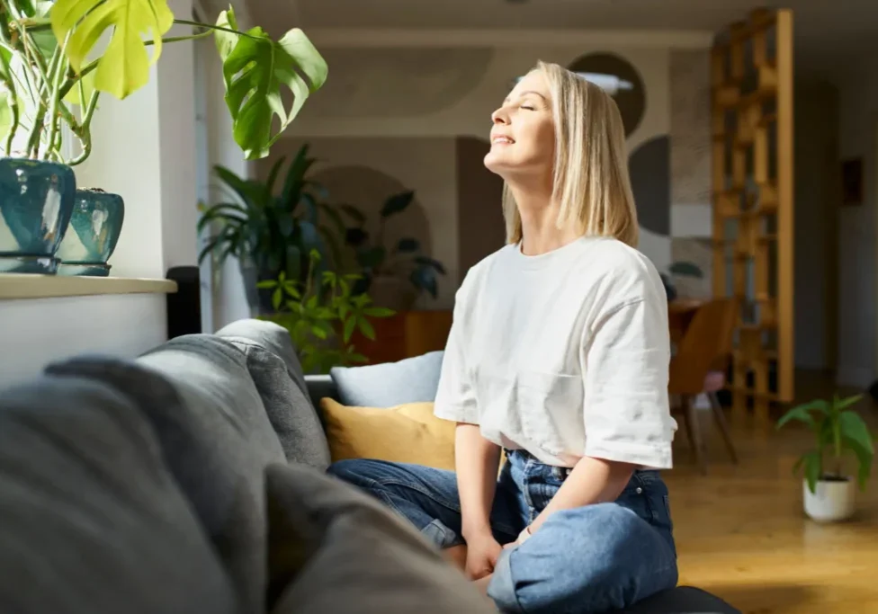 Woman enjoying sunlight on a cozy sofa.